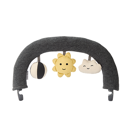 A gray baby bouncer toy arch with hanging plush toys: a black and white circle, a smiling yellow sun, and a happy white cloud.